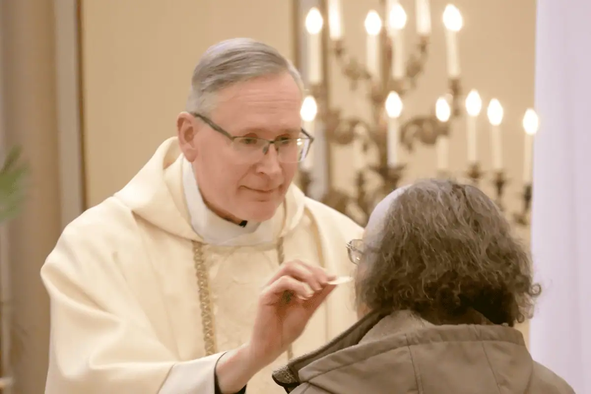 Priest giving a woman the Eucharist.